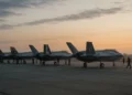 Lineup of F-35 Lightning II jets on tarmac featuring flags of allied operators like USA, UK, Italy, and Japan