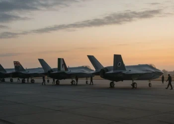 Lineup of F-35 Lightning II jets on tarmac featuring flags of allied operators like USA, UK, Italy, and Japan