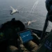 A USAF F-22 Raptor fighter jet flying alongside an autonomous MQ-20 Avenger drone during a Manned-Unmanned Teaming test.