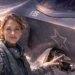 A female F-35 Lightning II fighter pilot in flight gear standing next to the cockpit of the stealth aircraft during sunset.