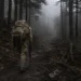 Exhausted soldier carrying a heavy ruck walks alone into a dark foggy forest after failing Special Forces Assessment and Selection (SFAS)